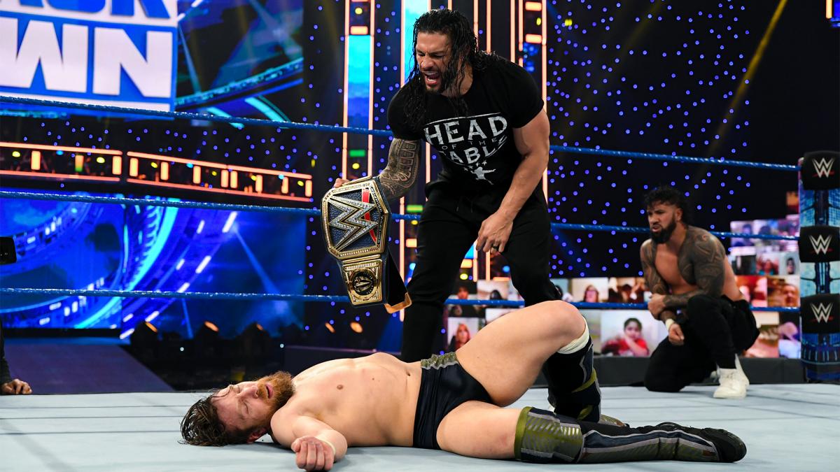 Universal Champion Roman Reigns poses over a fallen down Daniel Bryan with Jey Uso looking on WWE SmackDown February 2021